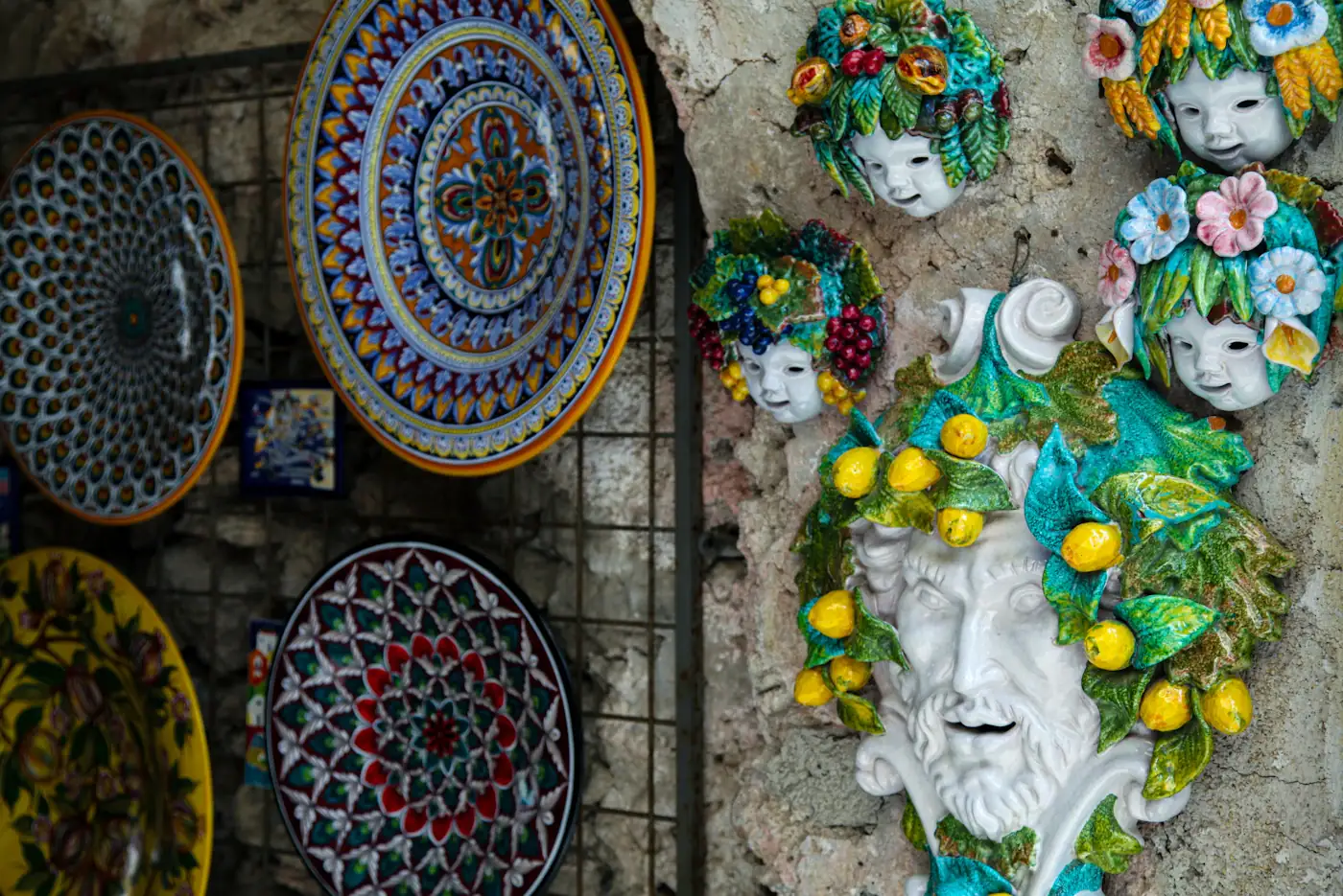 Painted ceramic plates and lemon-covered masks on a wall in Ravello.